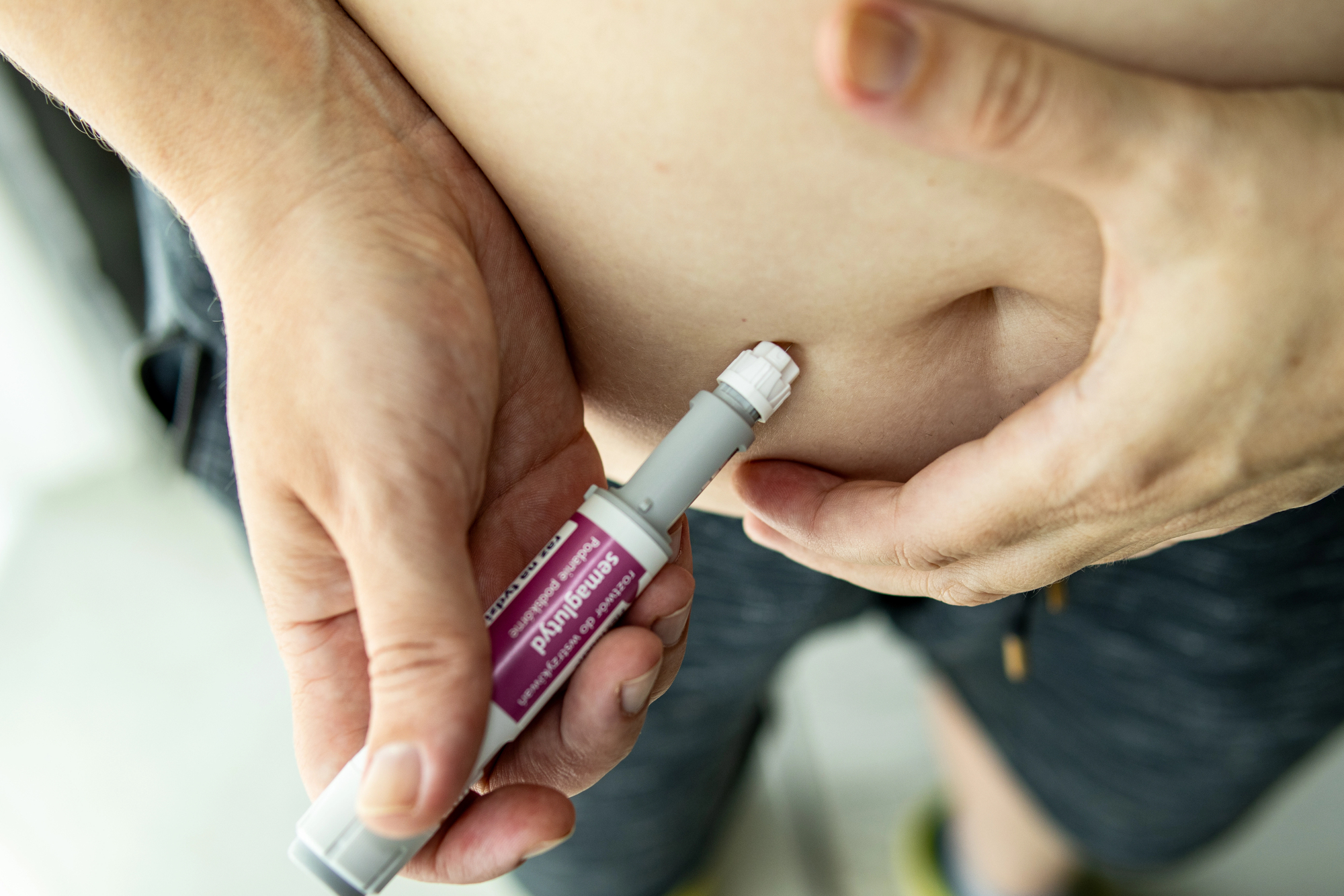 Depositphotos_830406080_L Wroclaw. Poland. 29.07.2025 Woman holding semaglutide injection pen in front of bare abdomen. Concept of obesity treatment, weight loss, and diabetes care.